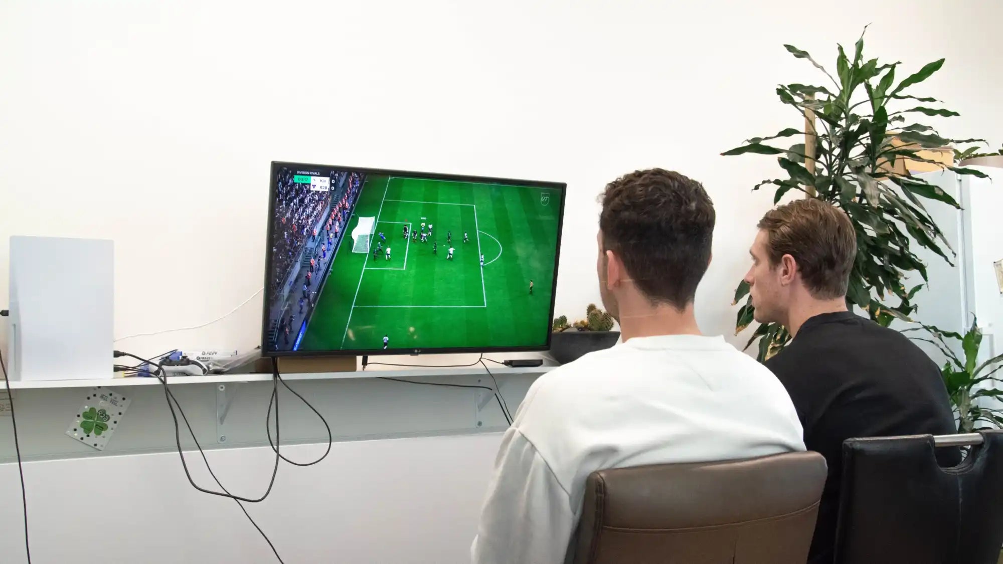 Twee mannen die een voetbalvideogame spelen.